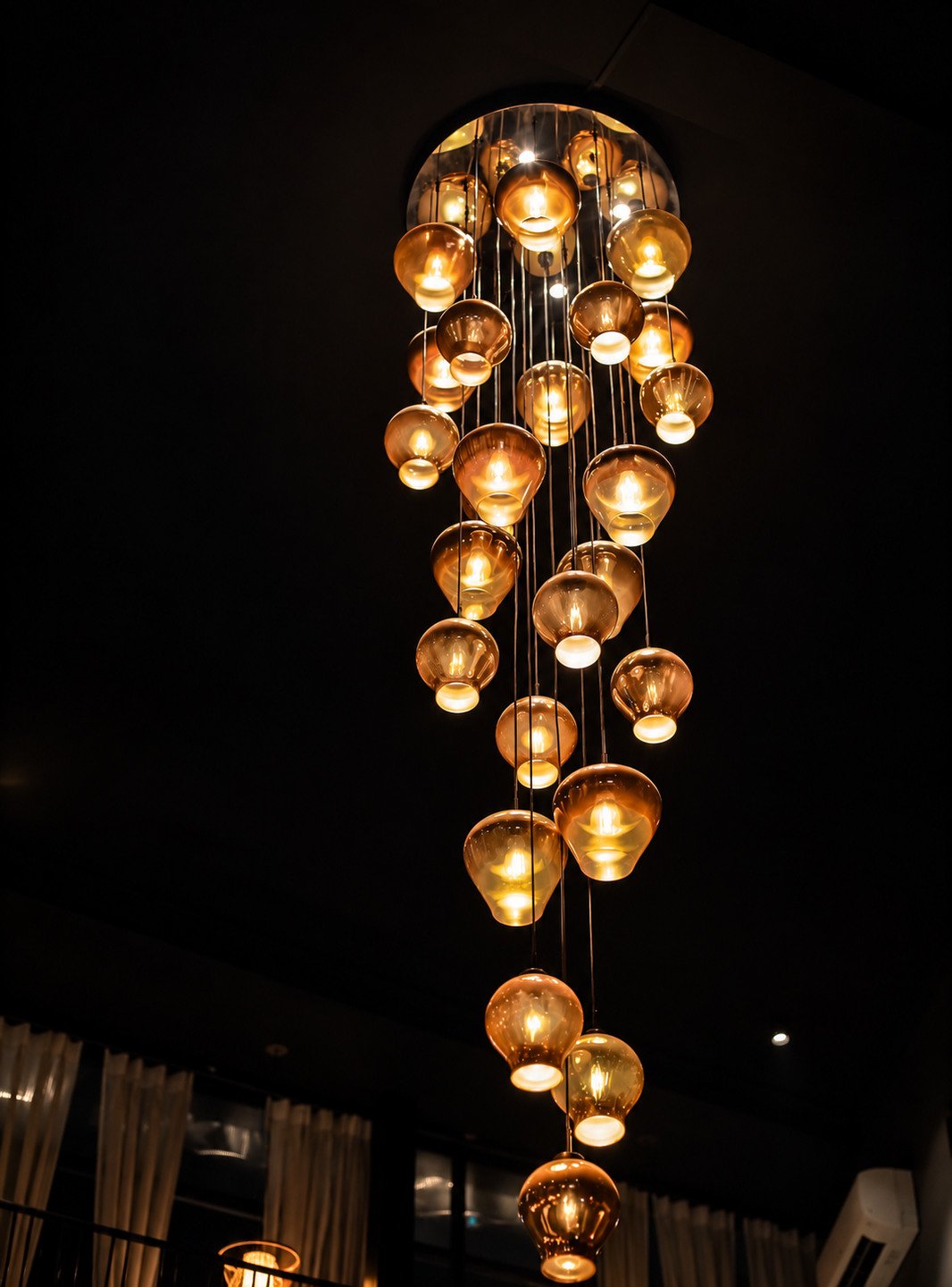 The cascade of glass lamps over the dining room at night